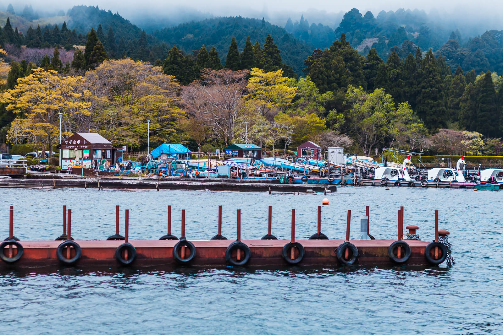 Pier at Lake Ashinoko in Hakone with moored boats and lush greenery in the background.