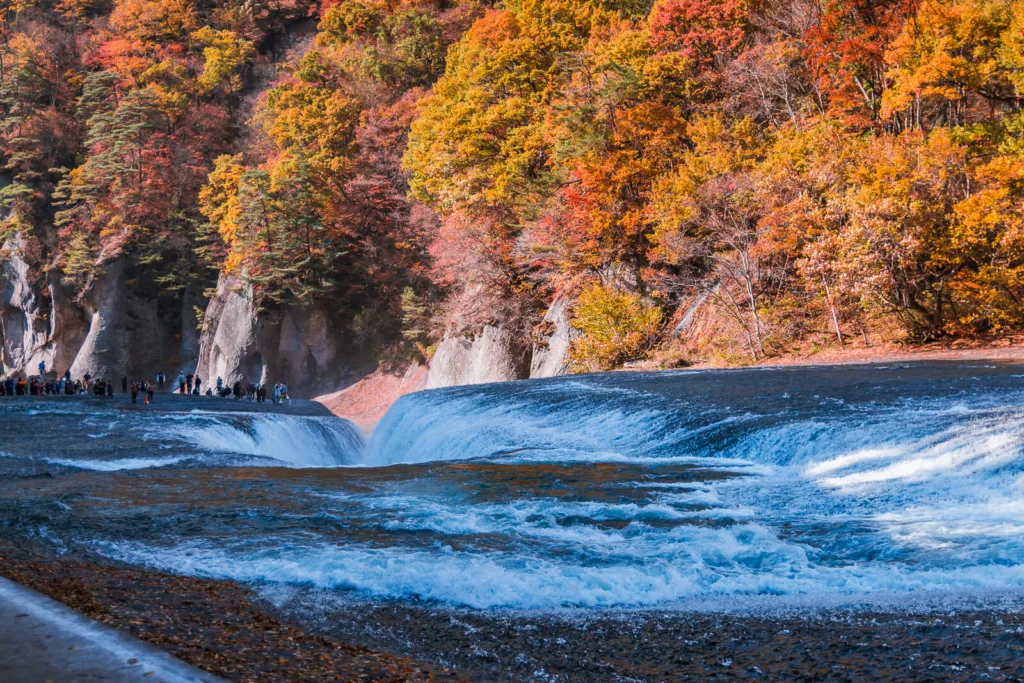 Fukiware Falls in Nikko surrounded by vibrant autumn leaves in the background.