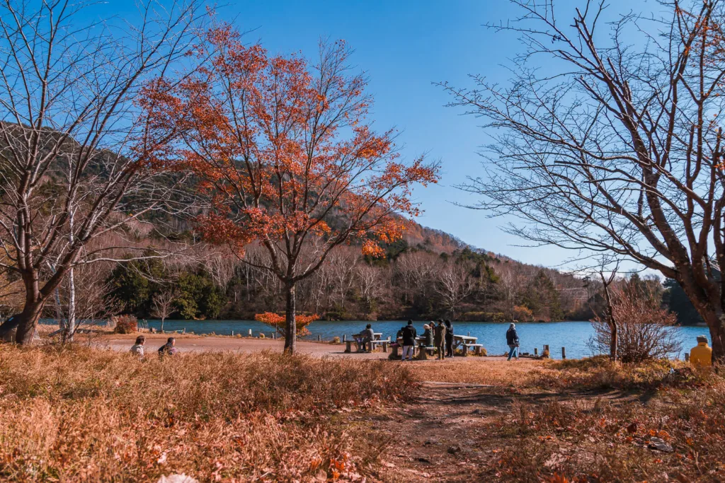 Lake Yunoko during autumn, with tourists enjoying the vibrant seasonal view under a clear daytime sky.