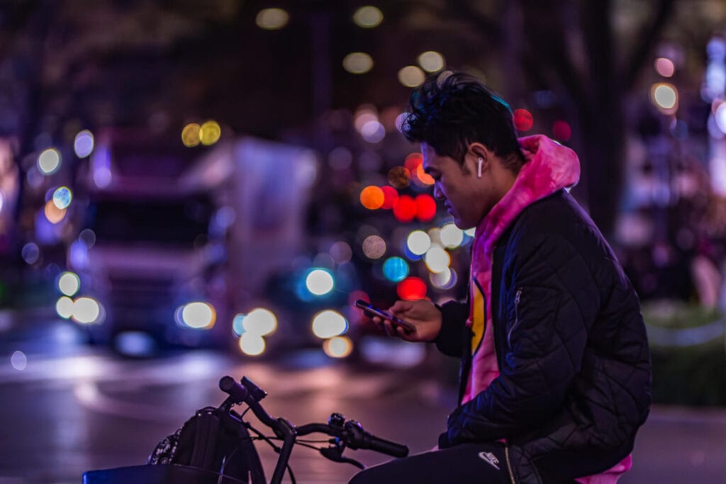 A guy waiting on cycle and scrolling his mobile at Harajuku.
