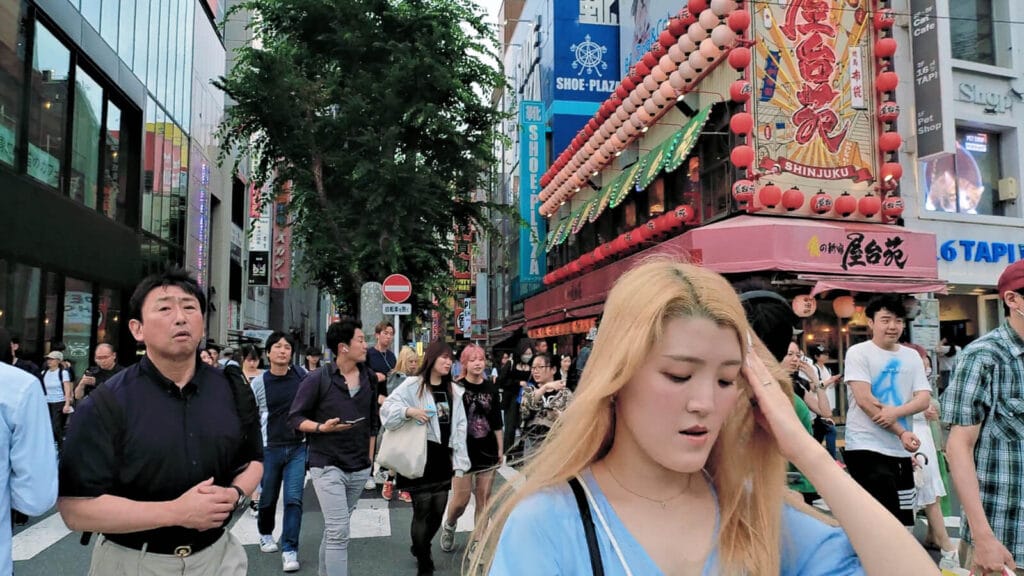 People crossing the road at a Shinjuku crossing near Cat Bilboard.